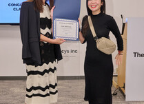A woman presenting another woman with a Lux and Nyx Certificate of Completion