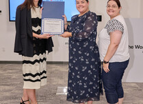 A woman presenting two people with a Certificate of Completion