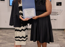 A woman presenting another woman with a Vaila Shoes Certificate of Completion