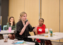 A workshop attendee with a microphone speaks during the workshop