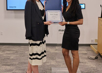 A woman presenting another woman with a Brown Toy Box Certificate of Completion