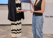 A woman presenting another woman with a Max-Min Certificate of Completion