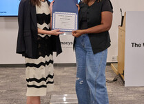 A woman presenting another woman with a Panty Buddy Certificate of Completion