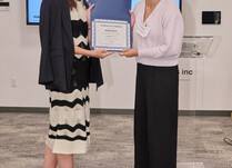 A woman presenting another woman with a Poplinen Certificate of Completion