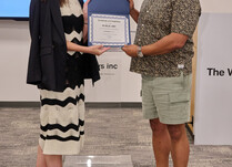 A woman presenting a man with a Public Art Certificate of Completion