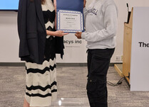 A woman presenting another woman with a Roam Load Certificate of Completion