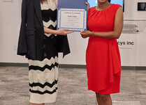 A woman presenting another woman with a Sawa Sawa Certificate of Completion