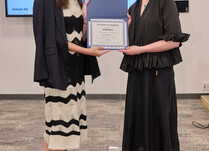 A woman presenting another woman with a Sparkies Certificate of Completion