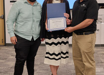 A woman presenting two people with an Uber Appliance Certificate of Completion