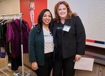 Two women posing by a clothing rack