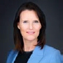 A person with dark hair wearing a blue jacket  Description automatically generated